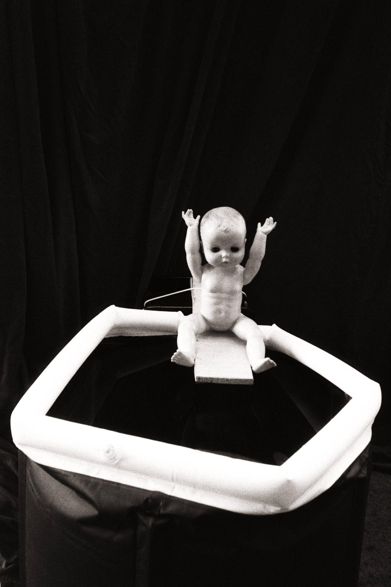 A baby doll sits above a makeshift dunk tank onstage